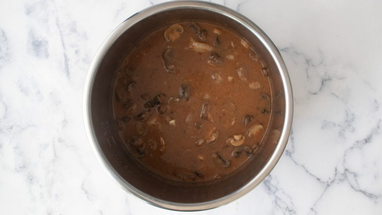 sauce with mushrooms and onions in a metal pot