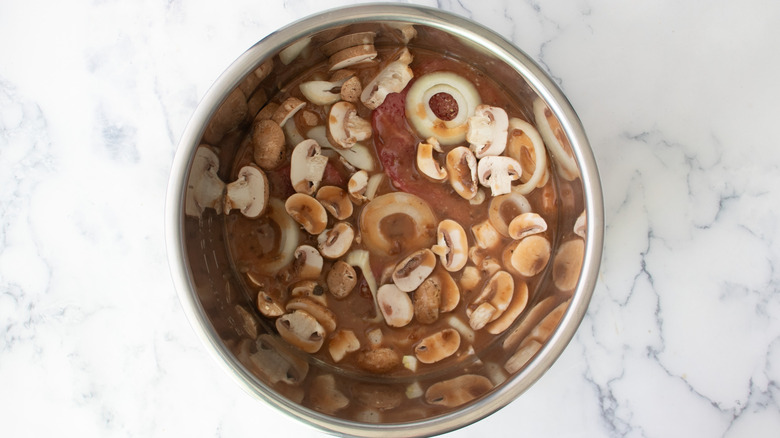 sauce with mushrooms and onions in a metal pot