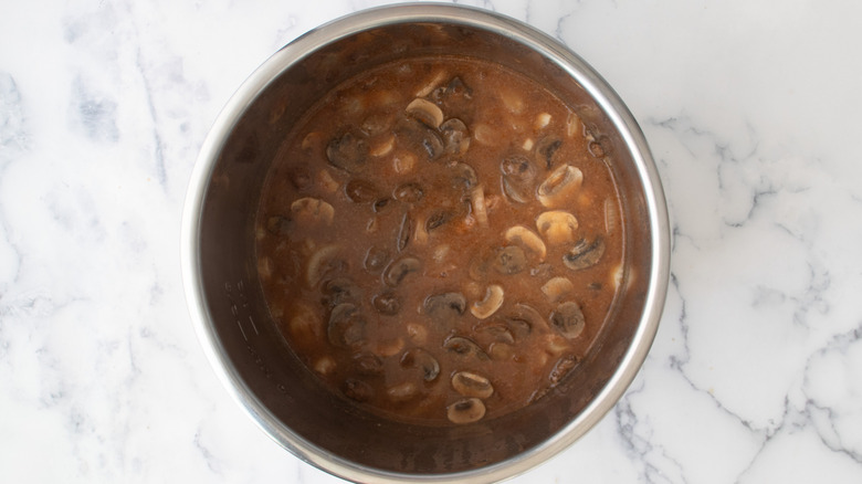 sauce with mushrooms and onions in a metal pot