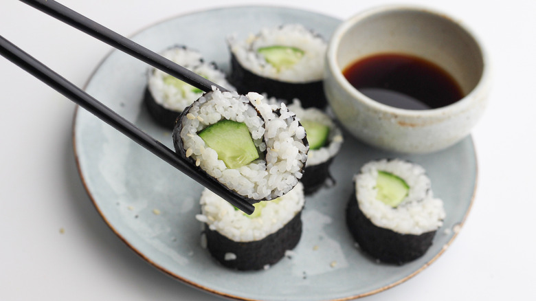 chopsticks holding sushi roll