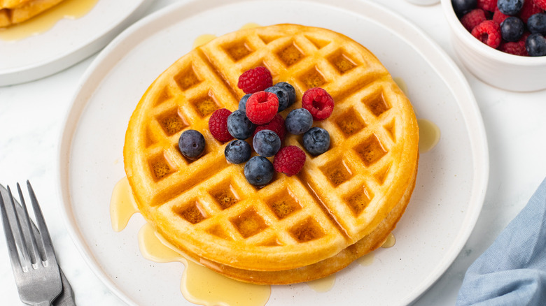 Waffles on plate with berries and syrup