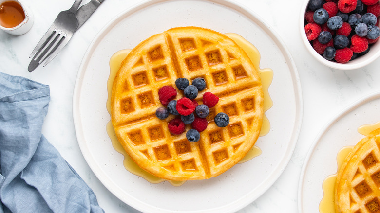 Waffle on plate with berries and syrup