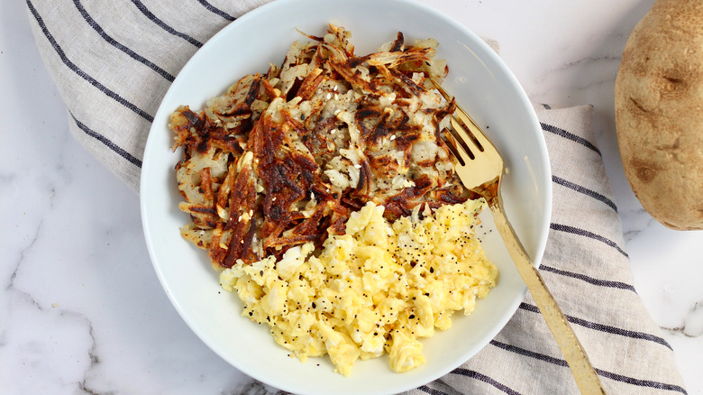 Hash browns and eggs on white plate