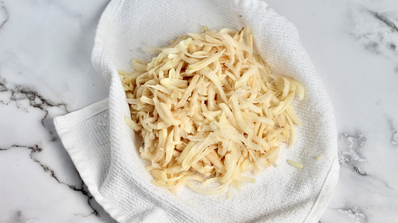 Shredded potatoes over white kitchen towel