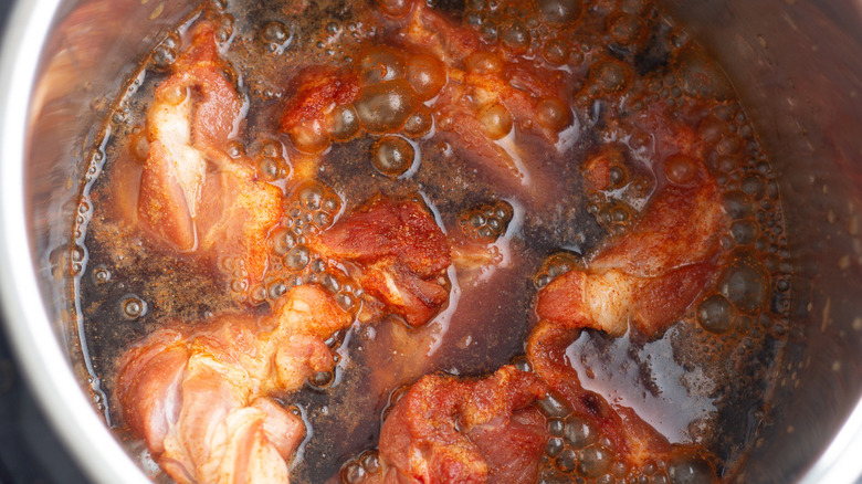 Bubbling liquid in a pot with pork