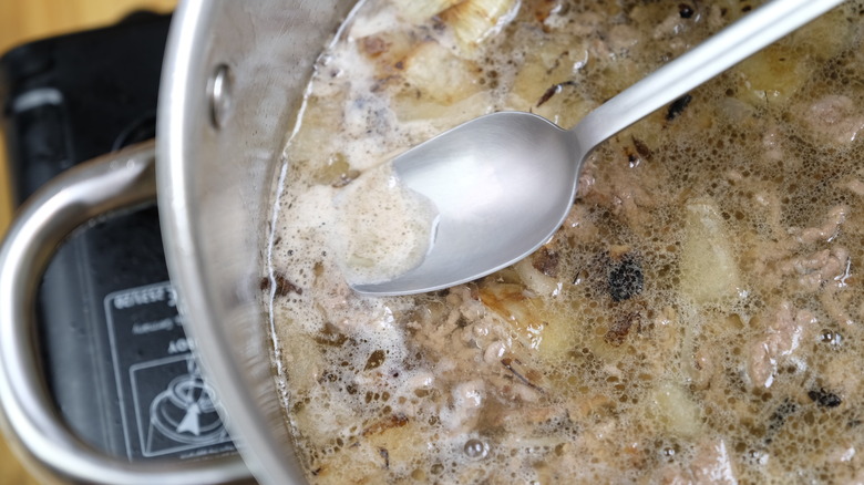 Removing scum from the top of the broth