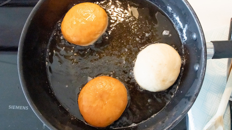 skillet of oil with three donuts in them