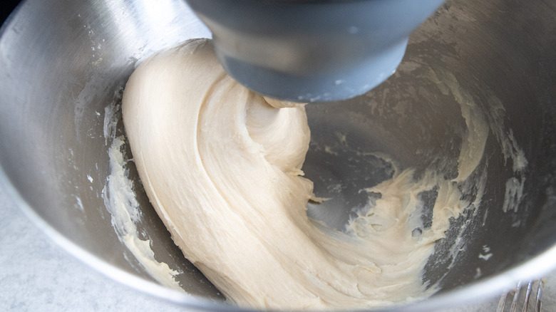 silver bowl of dough being blended by a mixer