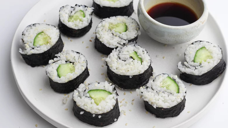 A plate of cucumber sushi rolls with soy sauce