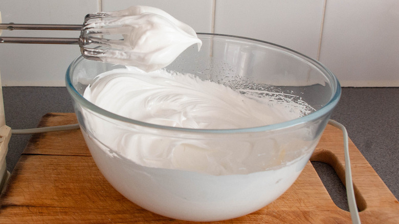 bowl of stiff egg white peaks on beaters above bowl