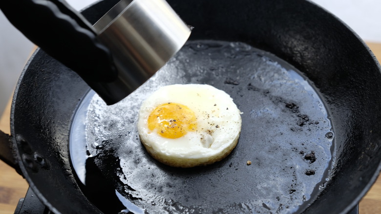 Egg shaped by egg ring cooking in pan 