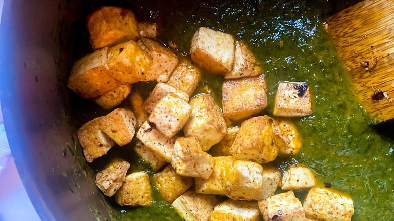 Mixing tofu and palak in bowl