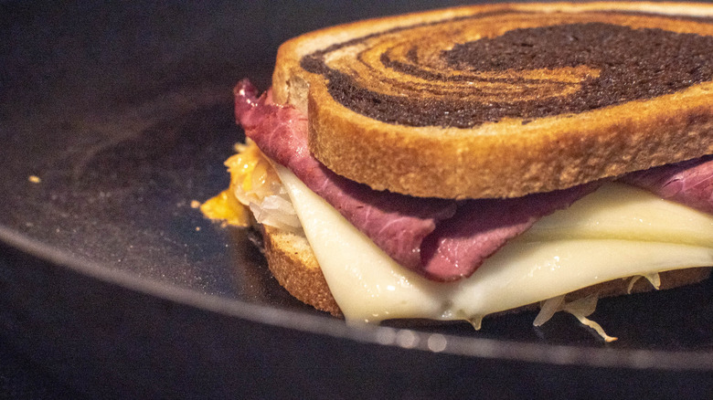 Reuben sandwich toasting in pan