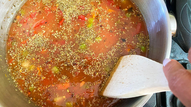 Soup cooking in a pot with oregano and tomatoes