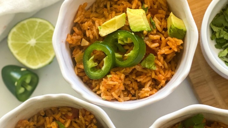  bowls filled with Instant Pot Spanish rice topped with slices of avocado and lime 