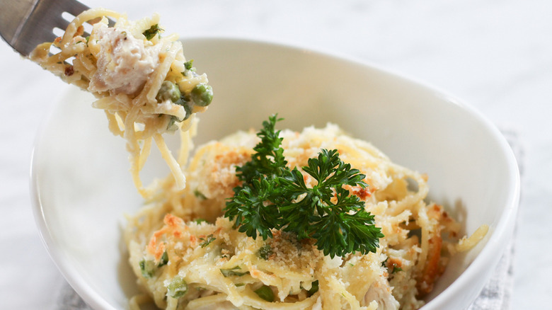 easy turkey tetrazzini wrapped around fork and in bowl with parsley garnish