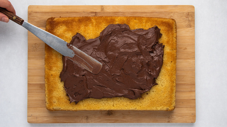 Spreading chocolate frosting on yellow cake