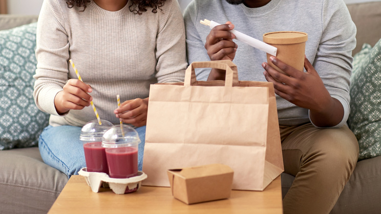 A couple digging into restaurant takeout food