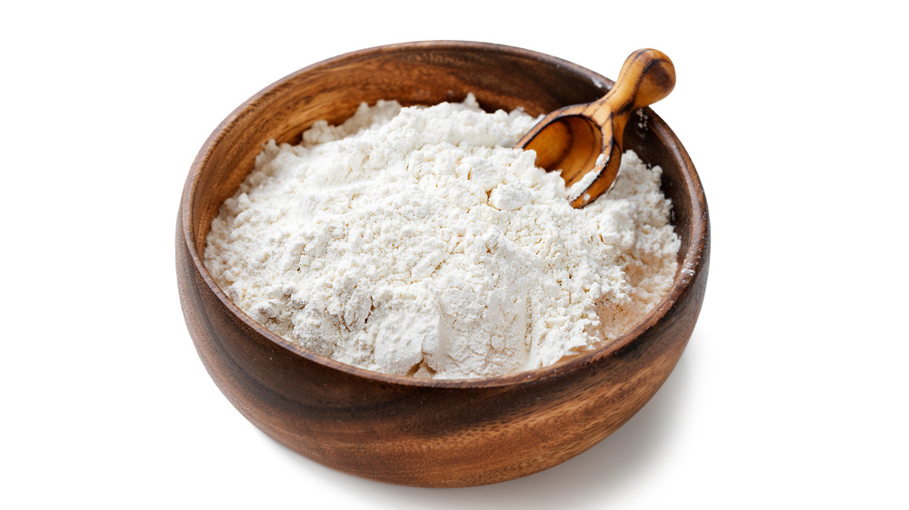 A bowl of flour with a scoop