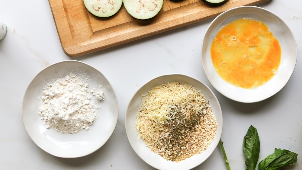 bowl of flour, egg, and breadcrumbs on counter for eggplant parmesan recipe