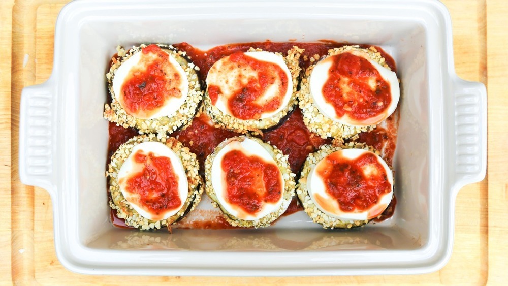 eggplant in stacks with toppings in pan for eggplant parmesan recipe