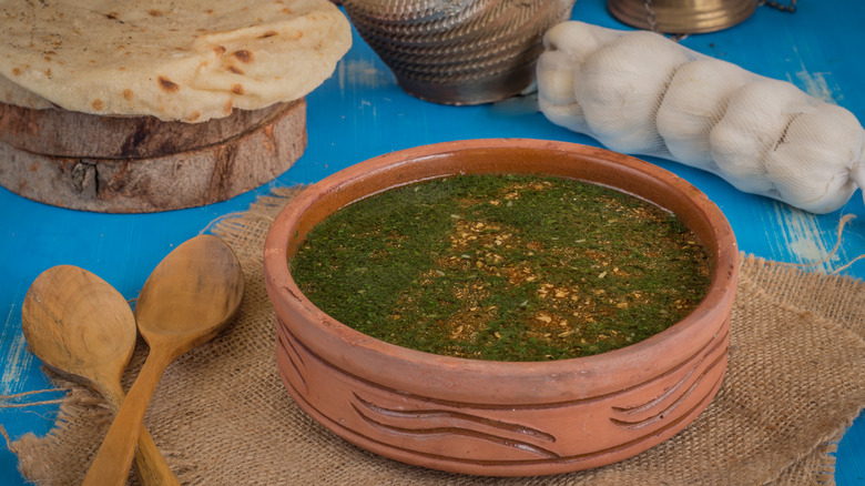 A bowl of Molokhia Soup with bread and garlic