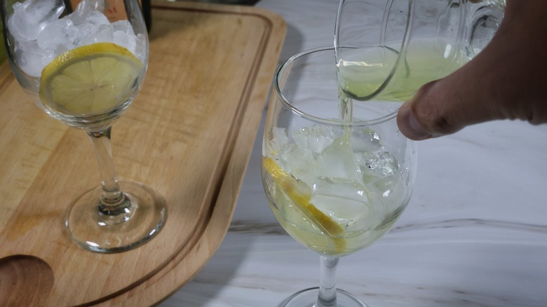 pouring limoncello into stemmed glass