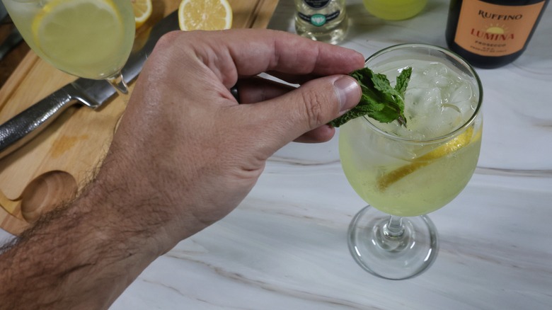 adding mint sprig to elderflower limoncello spritz