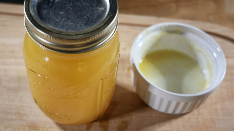 A sealed jar of whiskey and butter next to an empty ramekin