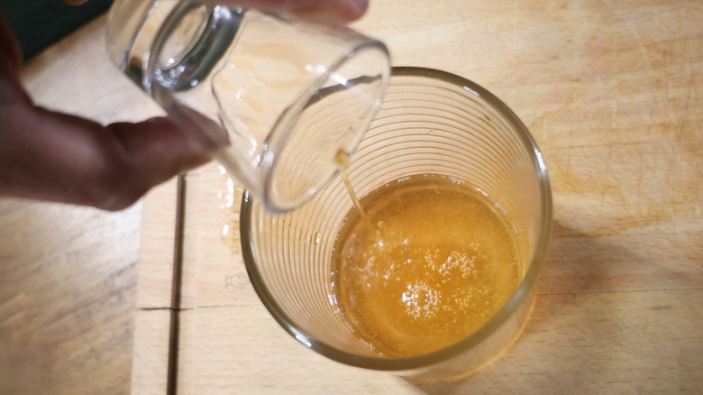 whiskey pouring out of shot glass into a rocks glass