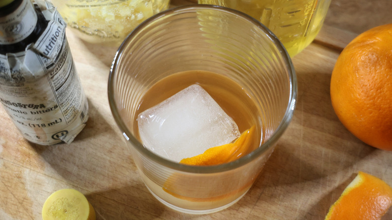 a butter washed old fashioned in a rocks glass with a large ice cube and a slice of orange peel