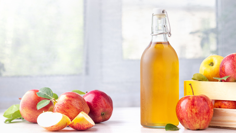 Bottle of apple cider next to apples