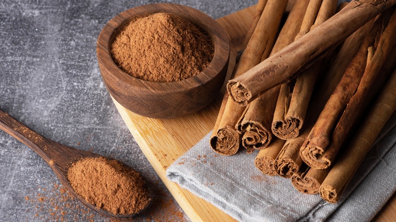 Cinnamon sticks next to bowl of cinnamon powder