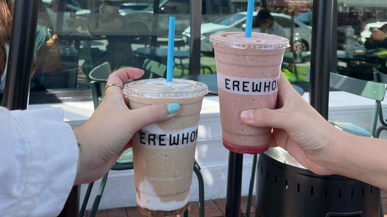 hands holding Erewhon smoothies