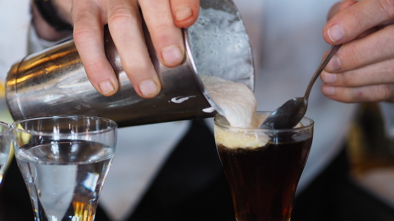 close up cream pouring over irish coffee whiskey 