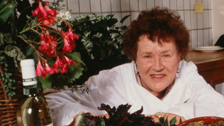 Julia Child  surrounded by lush greenery and bottle of wine