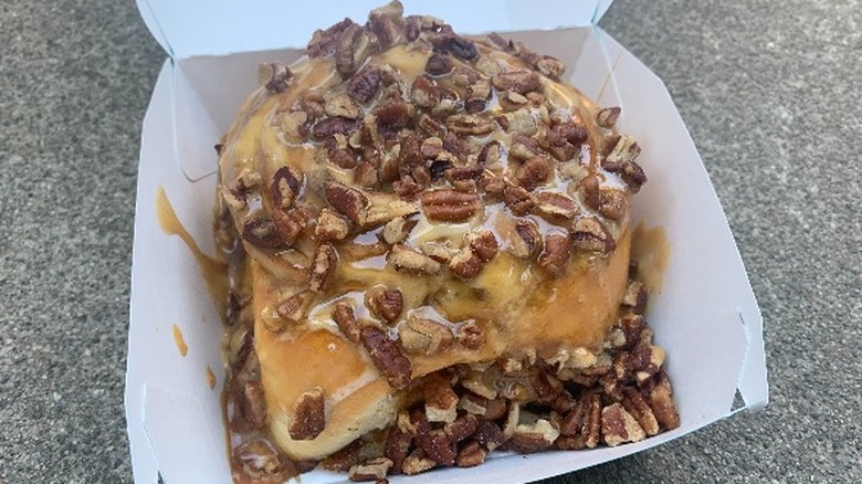 A large cinnamon roll covered in caramel and pecans