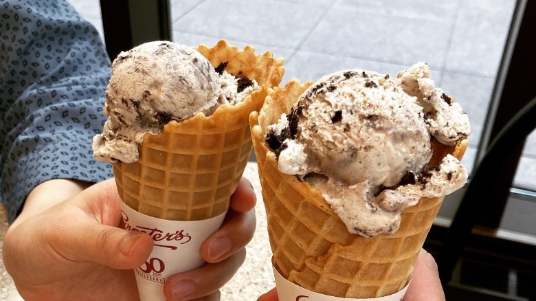 hand holding two cones cookies and cream ice