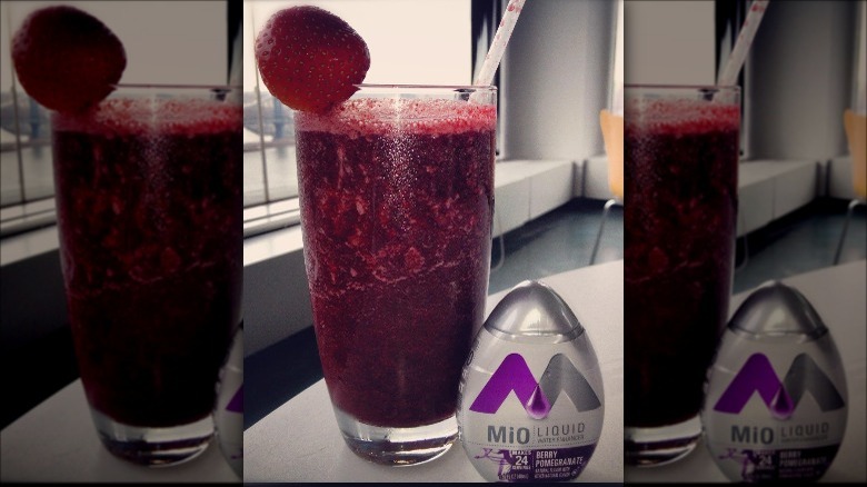 MiO Berry Pomegranate container next to glass with berry on top