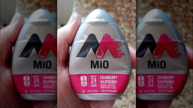 Someone holding MiO Cranberry Raspberry liquid water enhancer