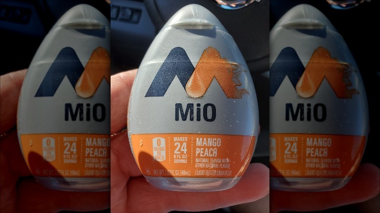 Someone holding MiO Mango Peach liquid water enhancer