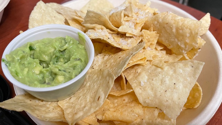 plastic cup of guac with tortilla chips