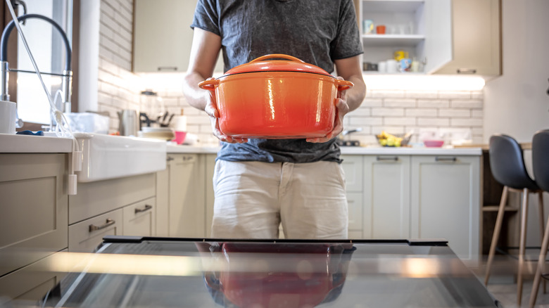 Man holding Dutch oven pot with oven POV