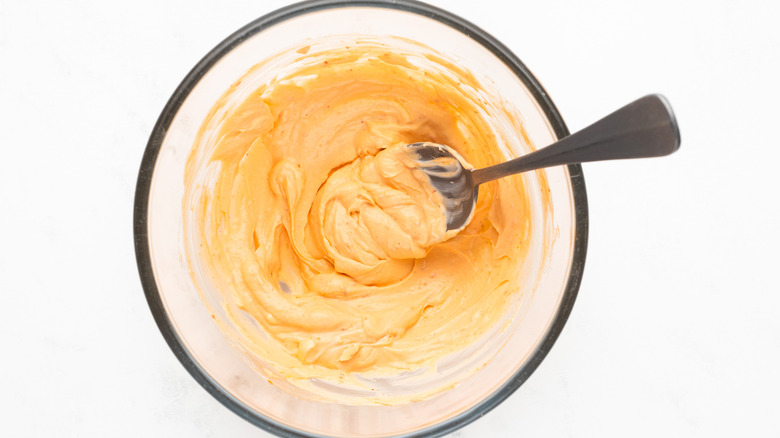 mixing sriracha cream cheese in bowl