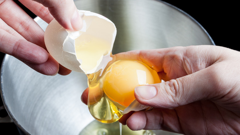 hands cracking open raw egg