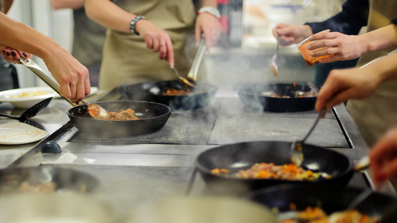 People cooking over a cooktop