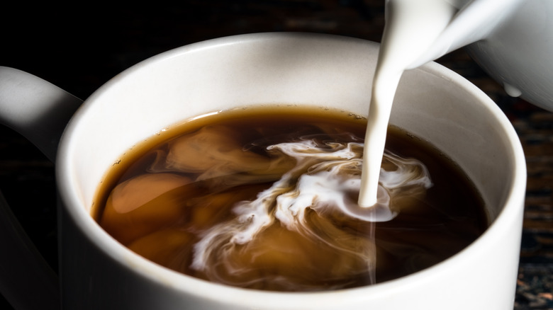 Pouring creamer into coffee