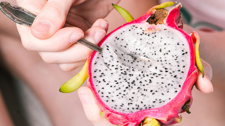 Half dragon fruit in hands with spoon