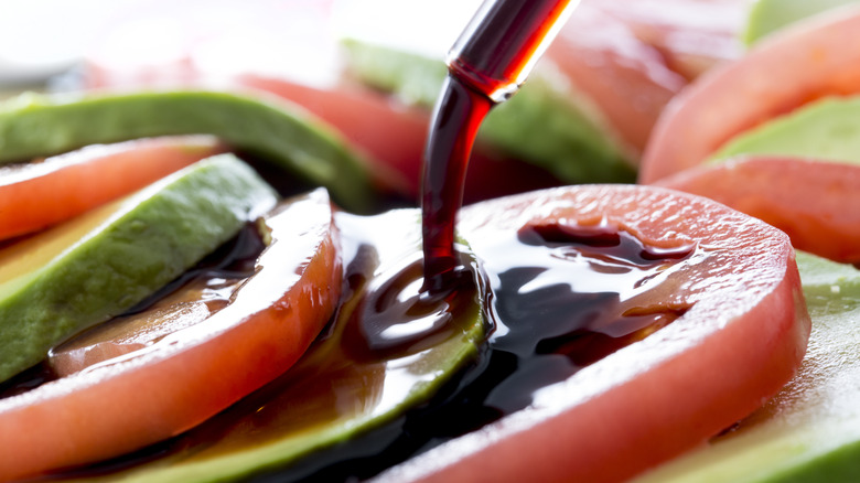 Balsamic vinegar being poured over sliced tomatoes