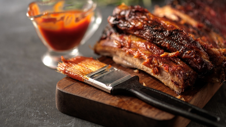 Ribs on a table being basted with sauce.